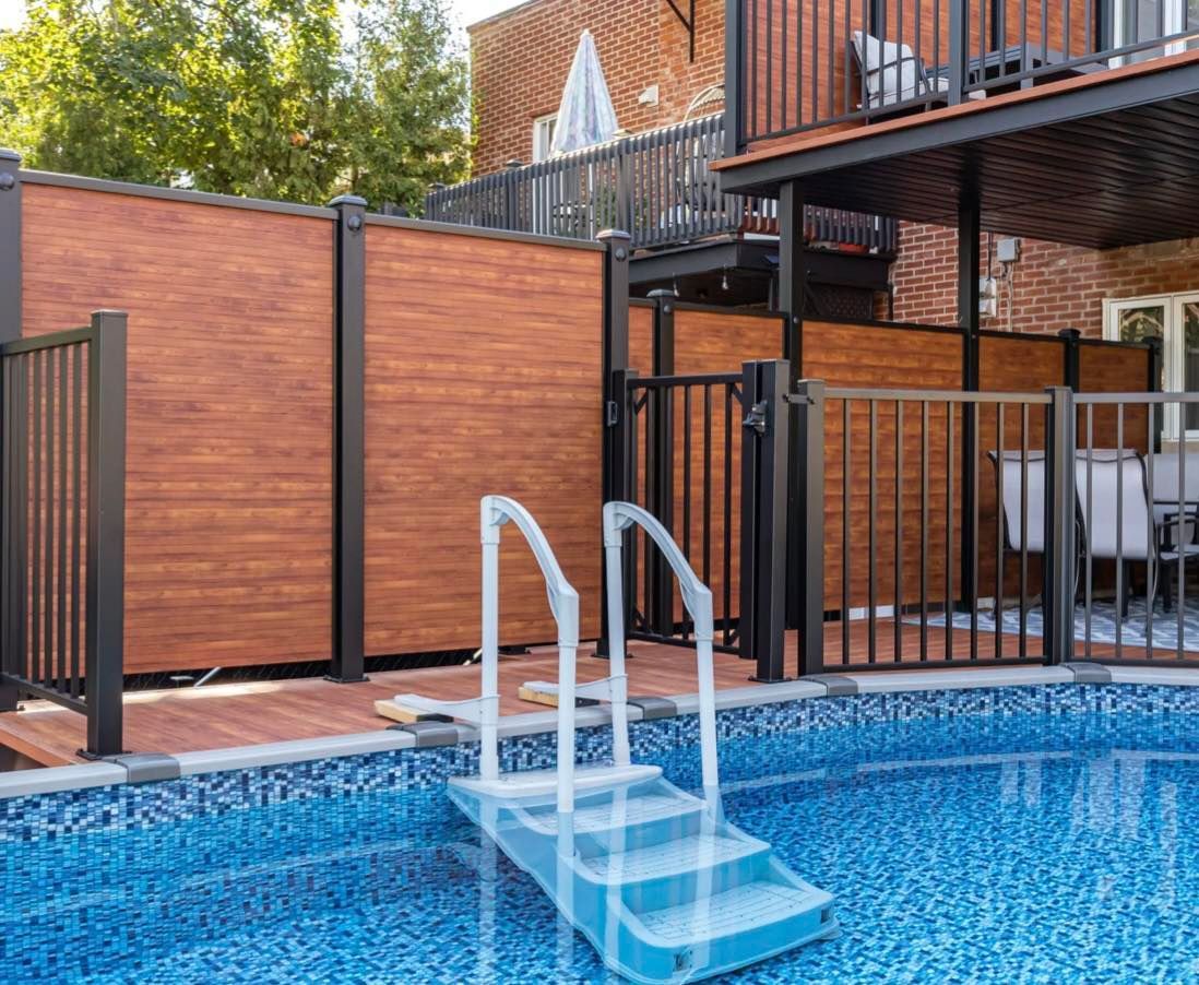 Une piscine avec une clôture en bois et des escaliers qui y mènent.