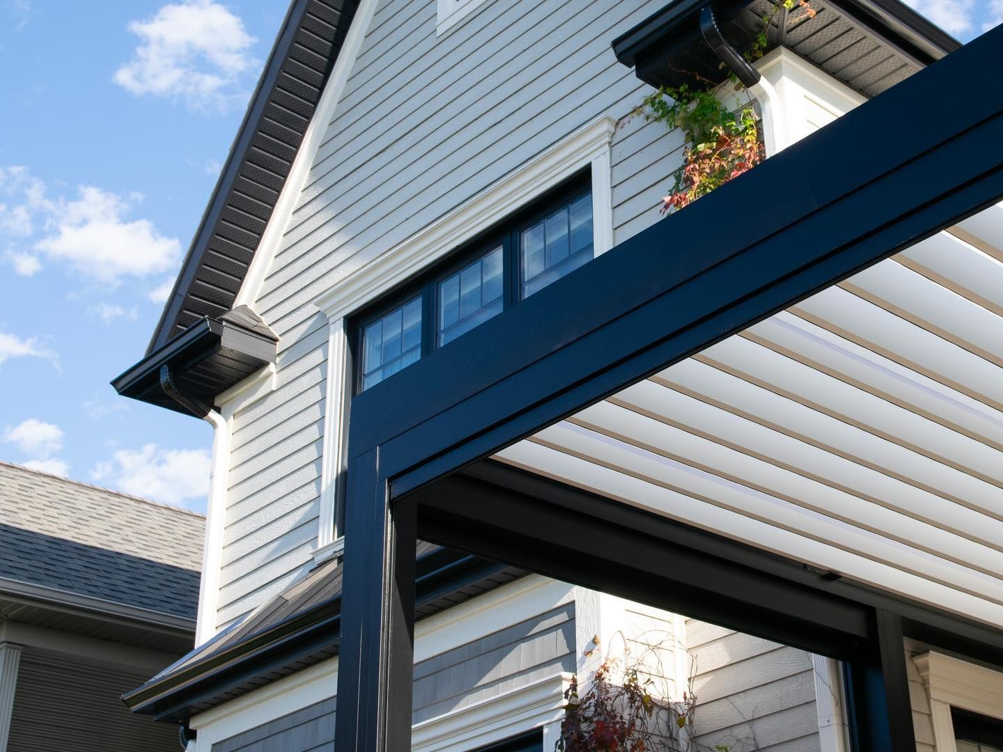 Une maison blanche avec un toit noir et un auvent bleu