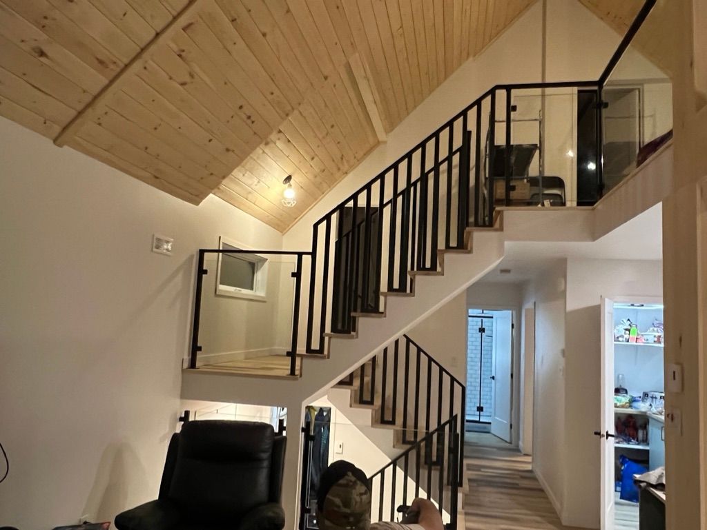 Un homme est assis sur une chaise dans un salon à côté d'un escalier.