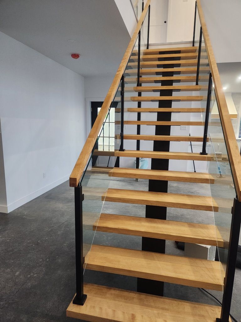 Un escalier en bois avec une rampe en verre dans une pièce.