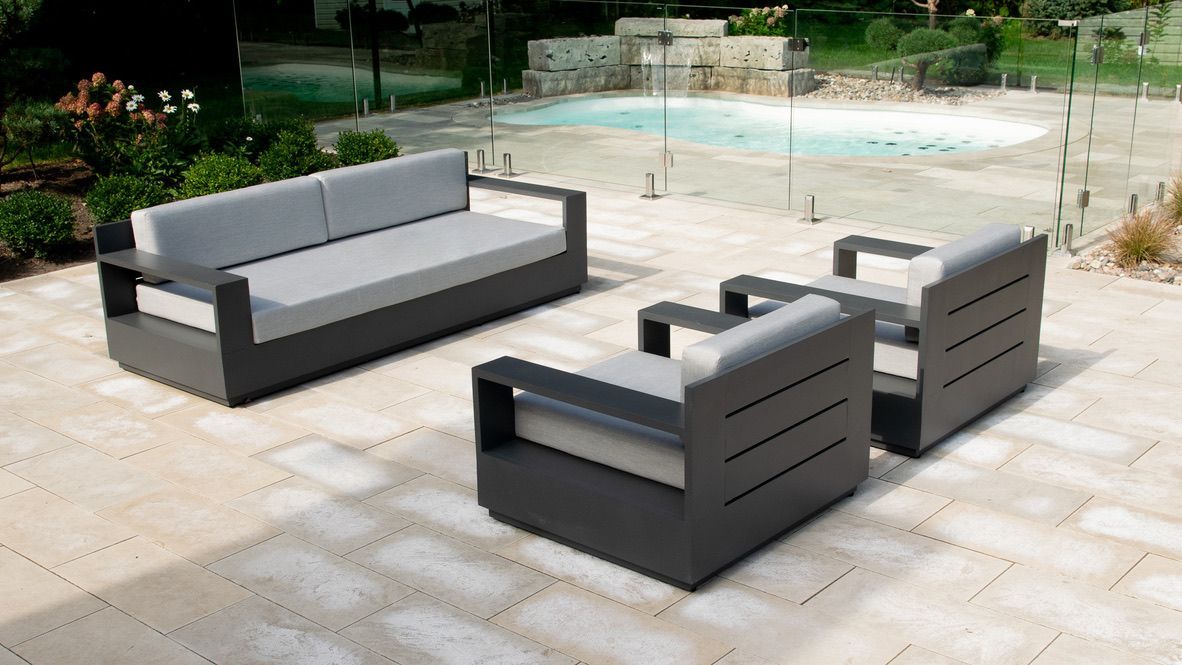 Un patio avec un canapé et des chaises à côté d'une piscine