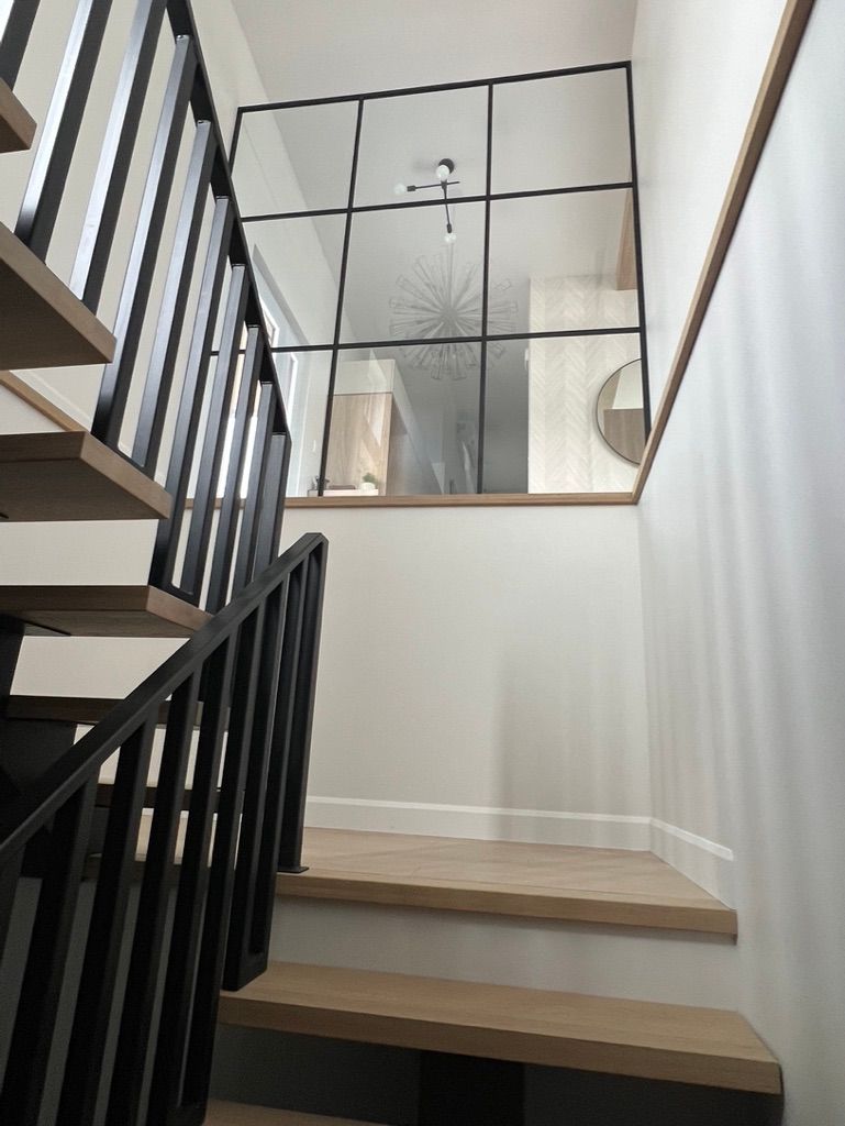 Les escaliers sont faits de bois et de métal et ont une paroi en verre entre eux.