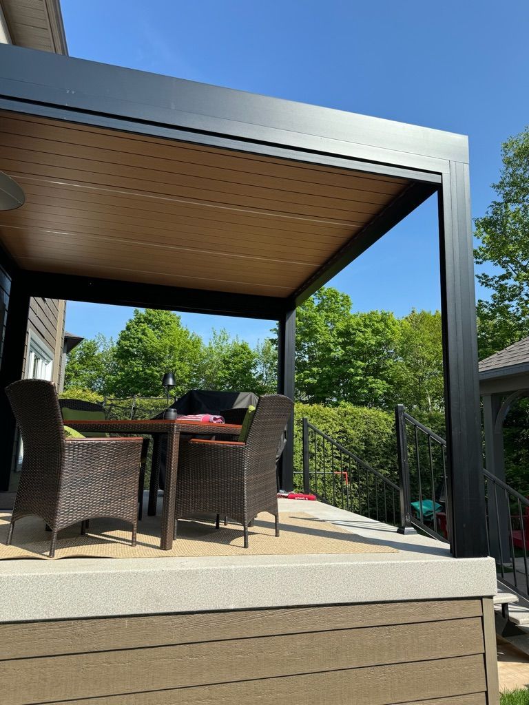 Un patio avec une table et des chaises sous une pergola.