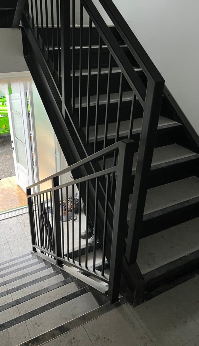 Un escalier noir avec une rampe et des marches en métal dans un bâtiment.