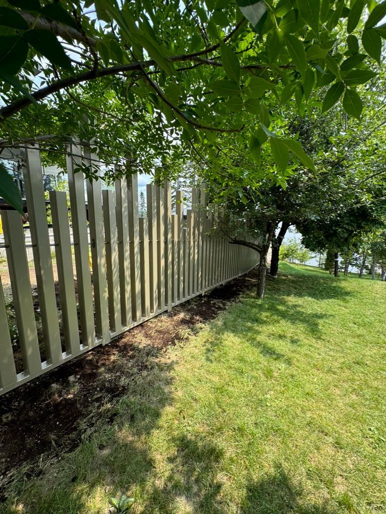 Une clôture blanche entoure une cour verdoyante.