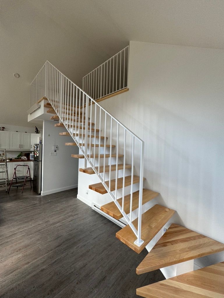 Un escalier en bois avec une rampe blanche menant au deuxième étage d'une maison.