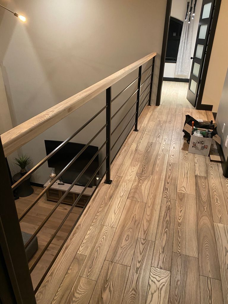 Un couloir avec parquet et rampe en métal.