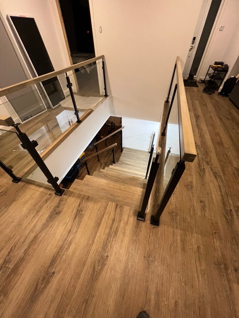 Un escalier en bois avec une rampe en verre dans une maison.