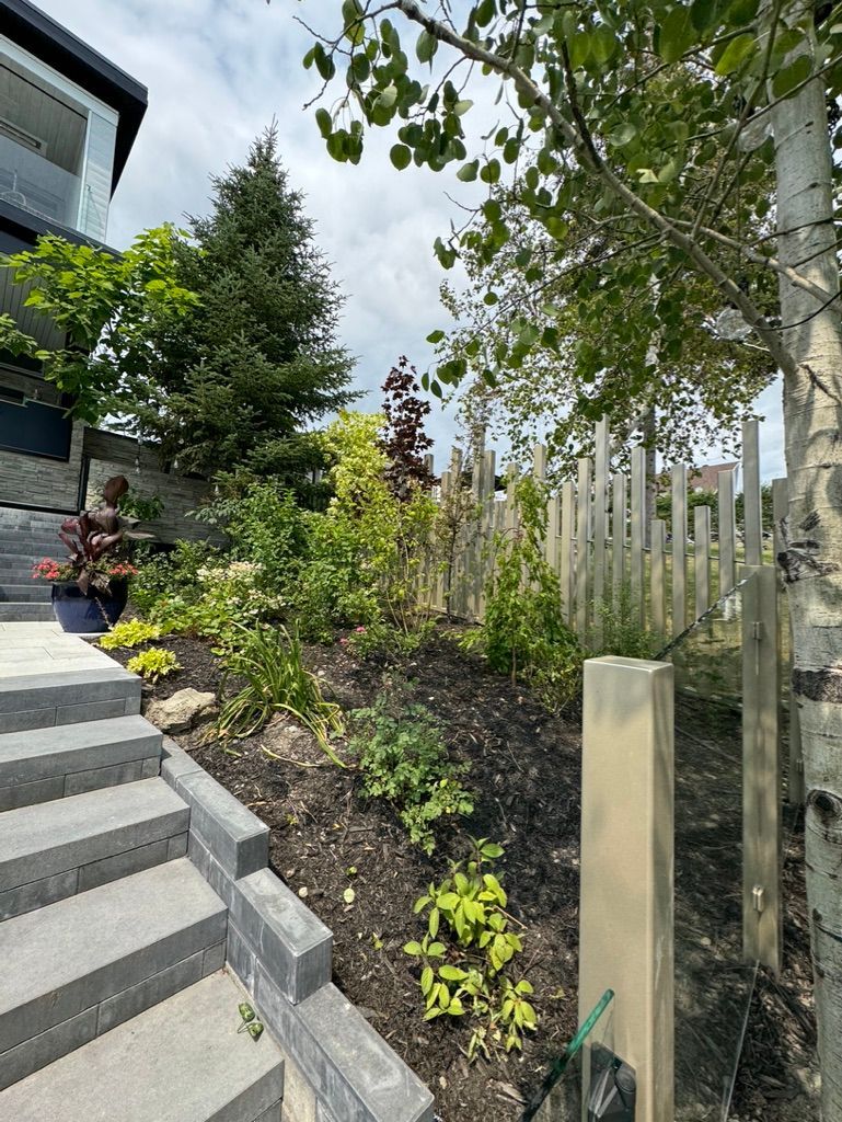 Un jardin avec des escaliers menant à une maison et une clôture en bois.