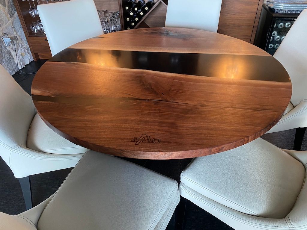 Une table ronde en bois avec des chaises blanches autour dans une pièce.