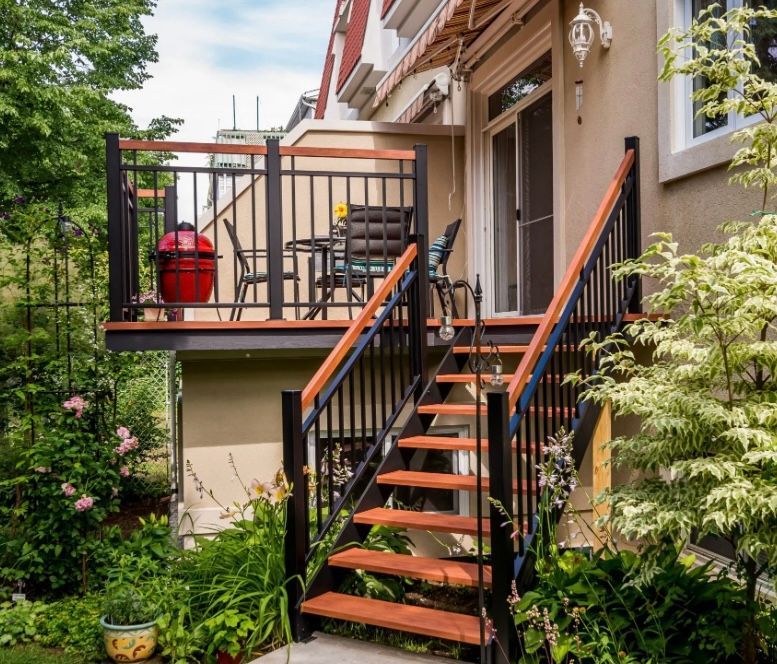 Une terrasse avec des escaliers qui y mènent et une table et des chaises dessus.