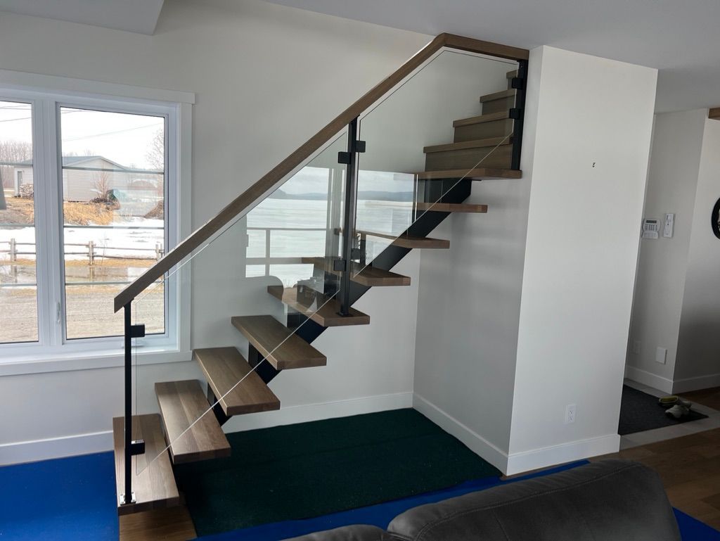Un escalier en bois avec une rampe en verre dans un salon.