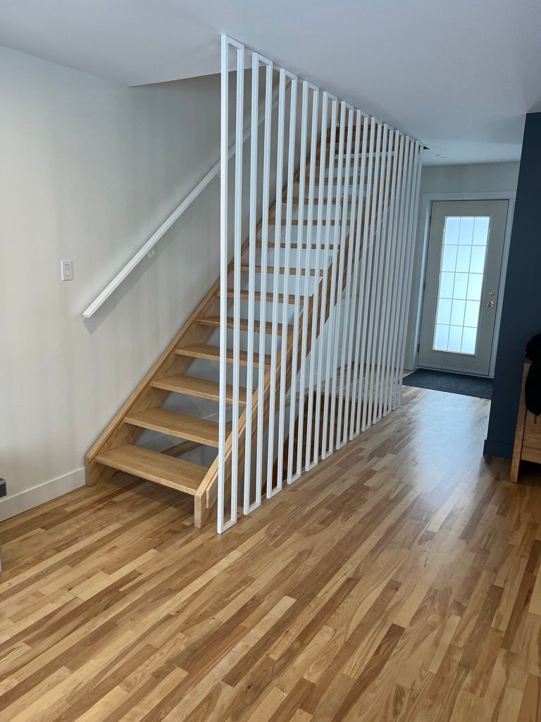Un escalier en bois avec une rampe blanche dans un salon.