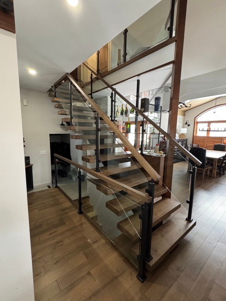 Un escalier en bois avec une rampe en verre dans un salon.