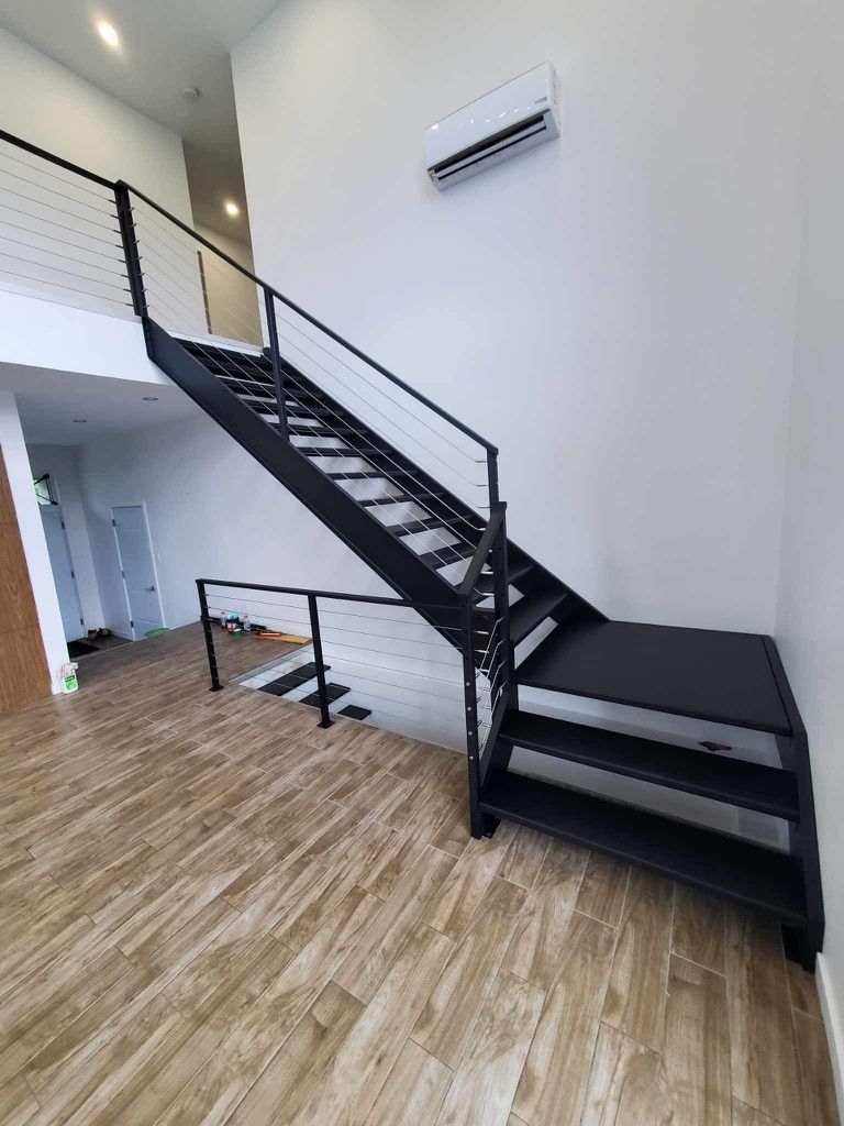 Un escalier noir dans une pièce avec un plancher en bois.