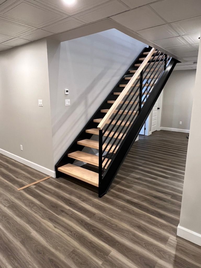 Un escalier dans un sous-sol avec des marches en bois et une rampe en métal.