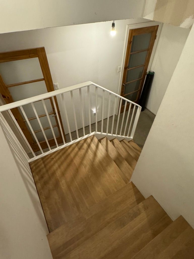 Un escalier avec une rampe blanche et des marches en bois