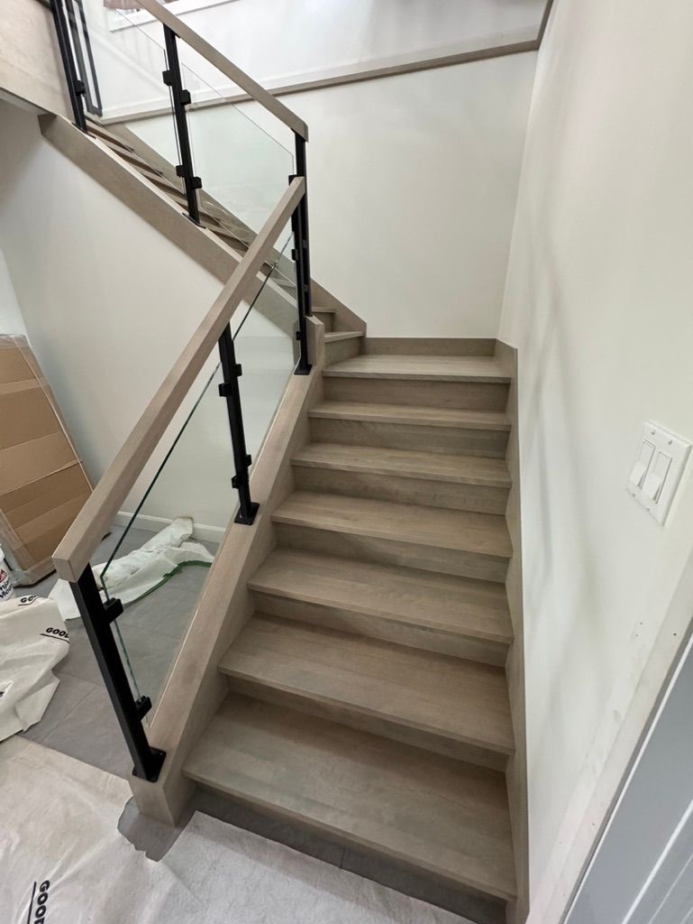 Un escalier en bois avec une rampe en verre dans une maison.