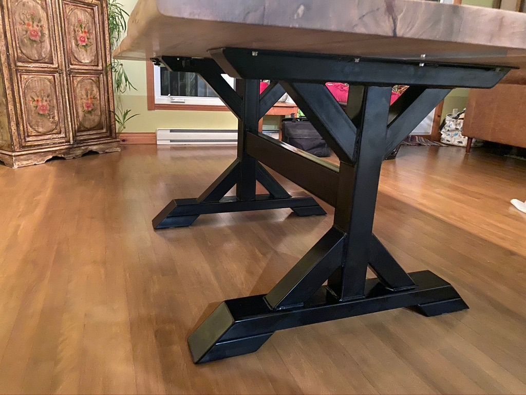 Une table en bois avec des pieds en métal noir est posée sur un plancher en bois dans un salon.
