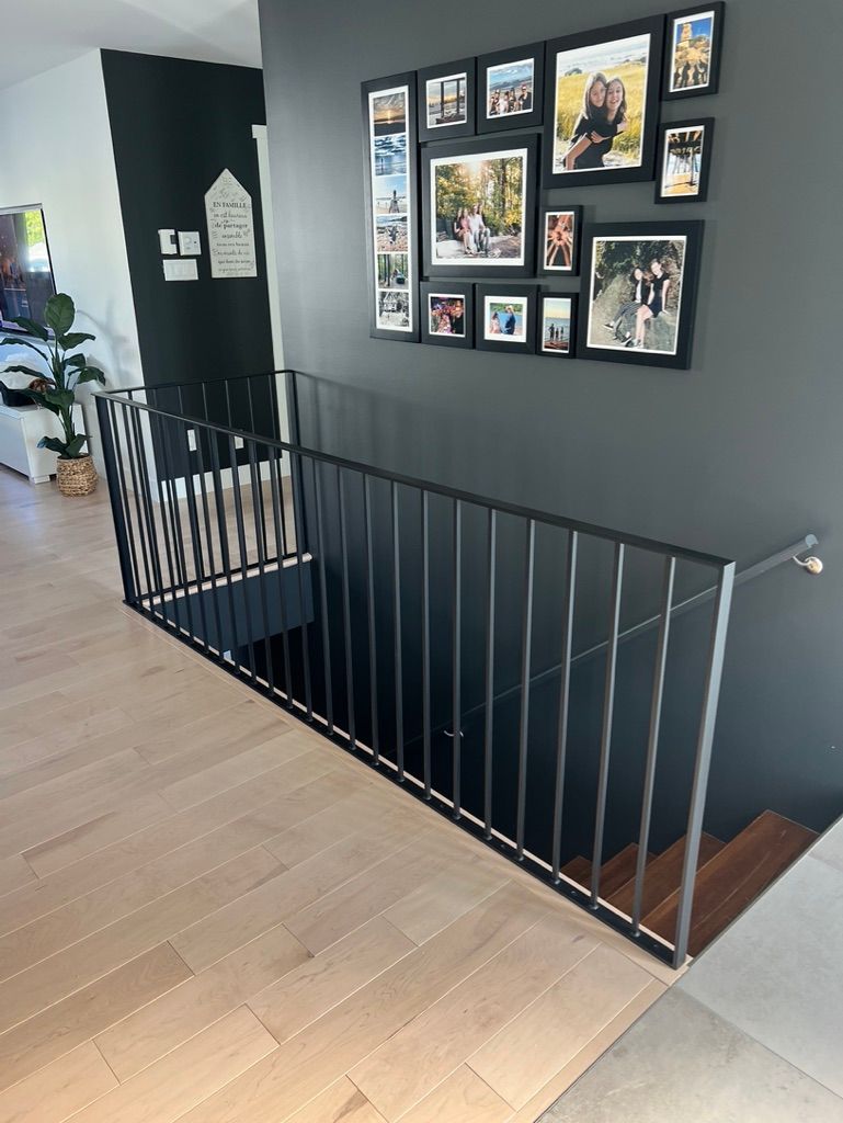 Un escalier avec une rampe et des tableaux au mur.