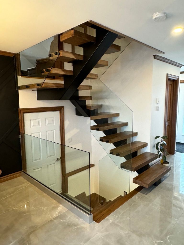 Un escalier en bois avec une rampe en verre dans une maison.