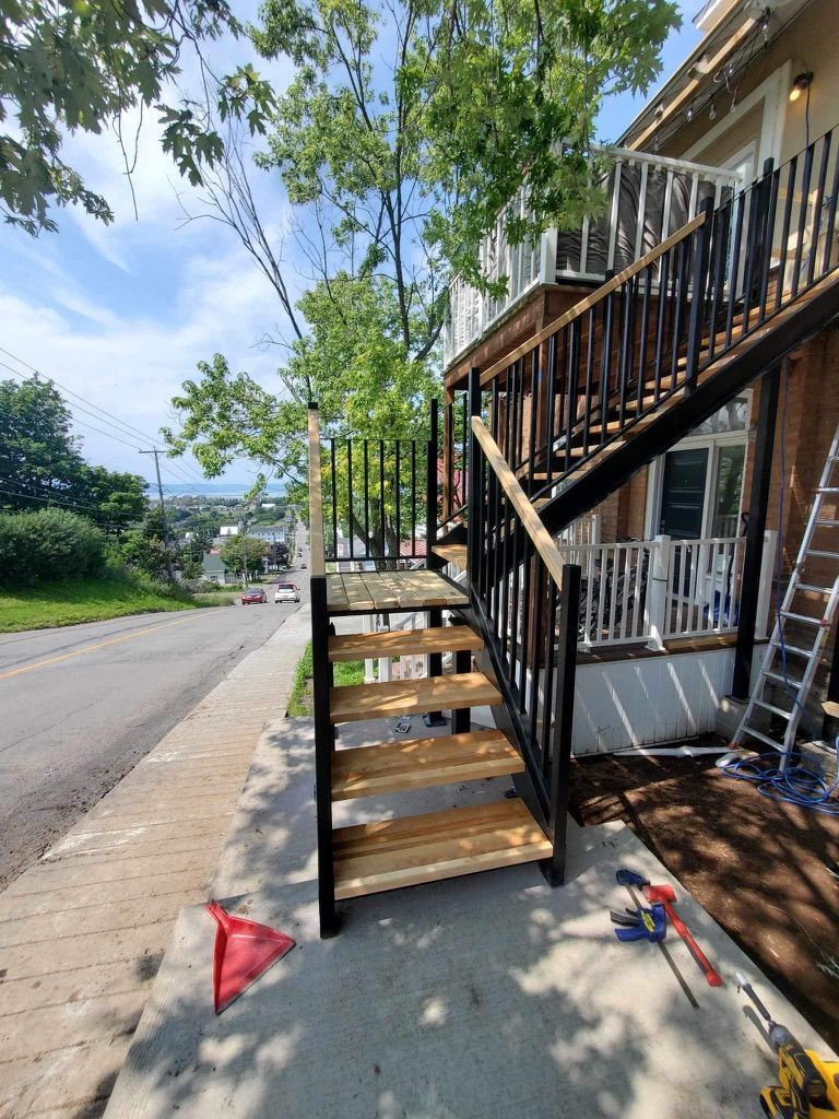 Un escalier en bois est en cours de construction sur le trottoir devant une maison.