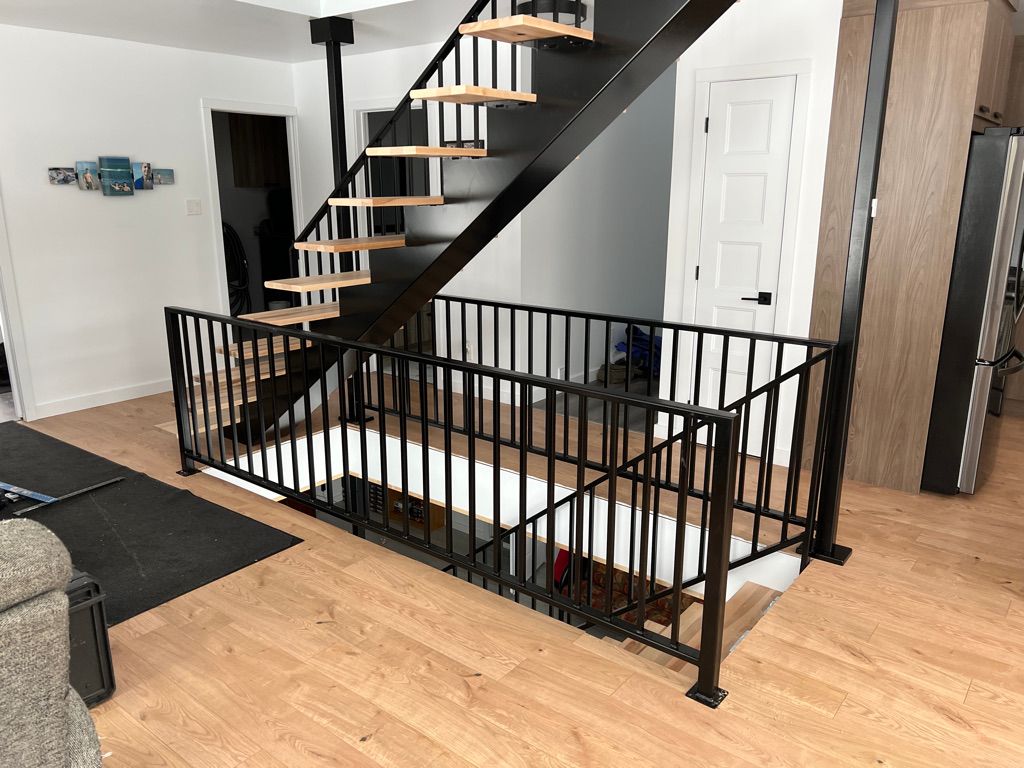 Un escalier noir avec des marches en bois et une rampe noire dans un salon.