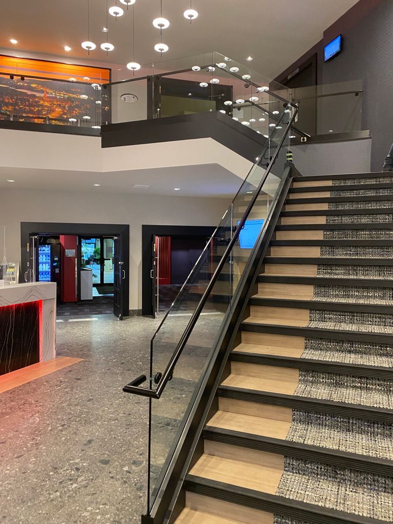 Un escalier avec une rampe en verre dans le hall d'un immeuble.