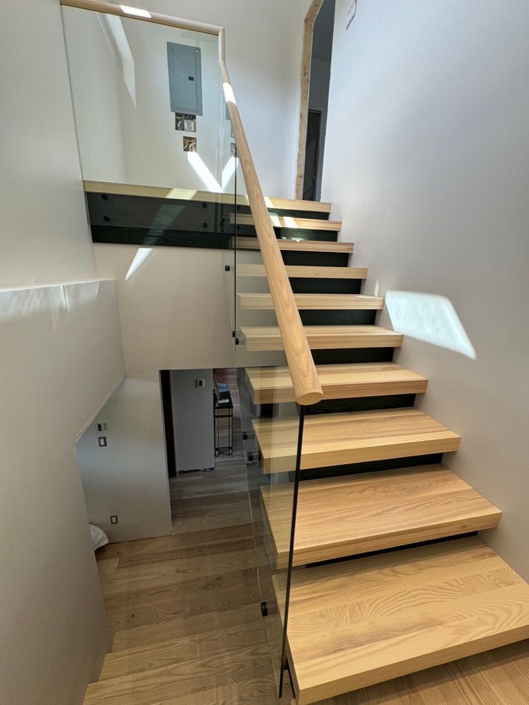 Un escalier en bois avec une rampe en verre dans une maison.