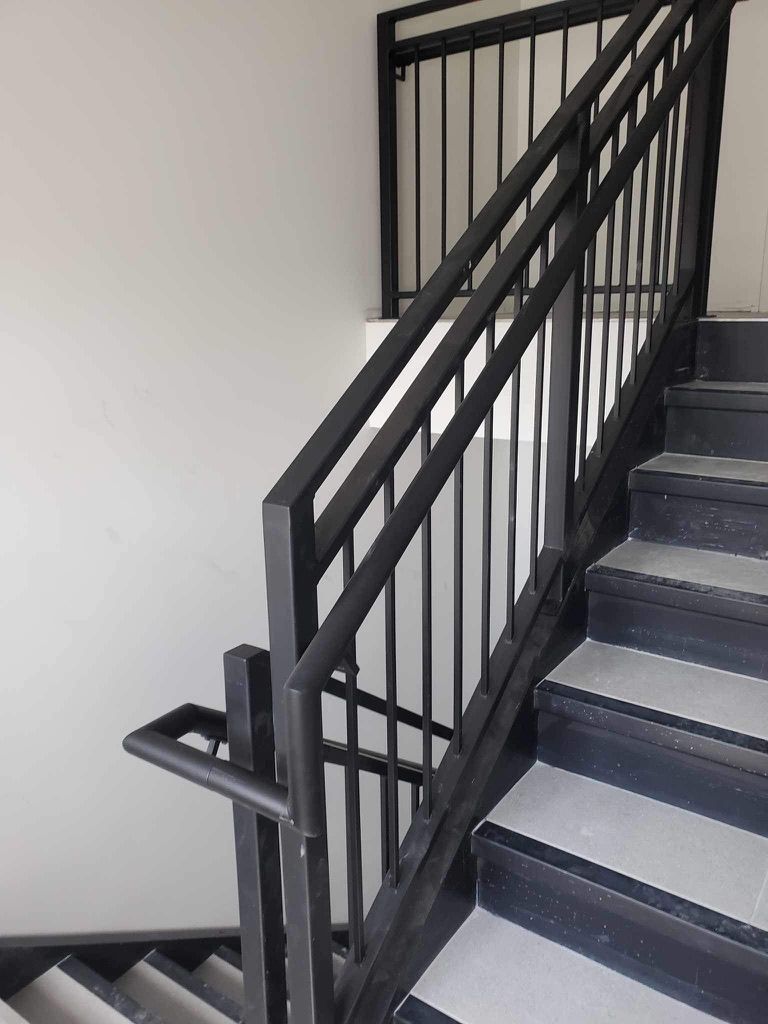 Un escalier avec une rampe noire et des marches dans un bâtiment.