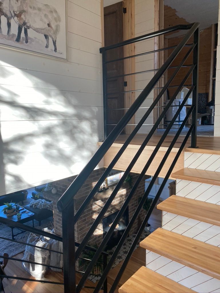 Un escalier avec une rampe noire et des marches en bois dans une maison.