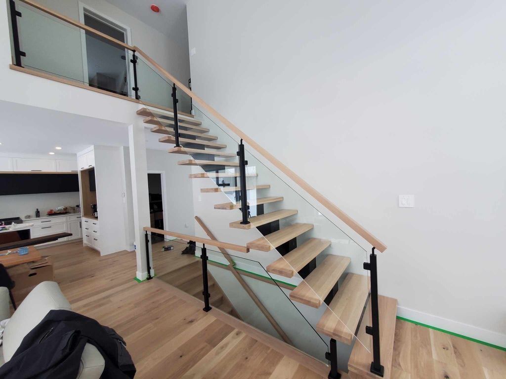 Un escalier en bois avec une rampe en verre dans un salon.