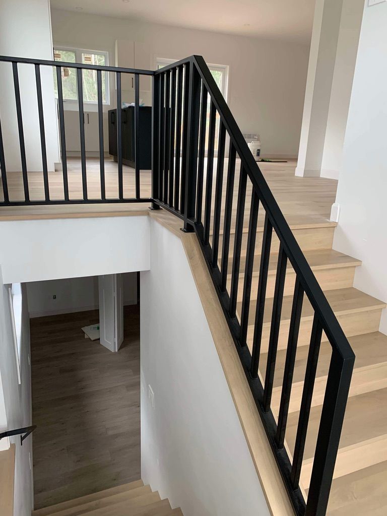 Un escalier avec une rampe noire et des marches en bois dans une maison.