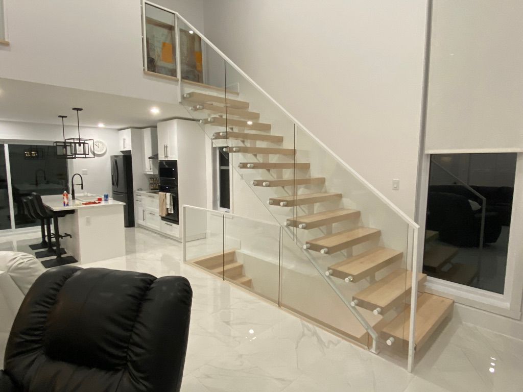 Un salon avec un escalier et une rampe en verre.