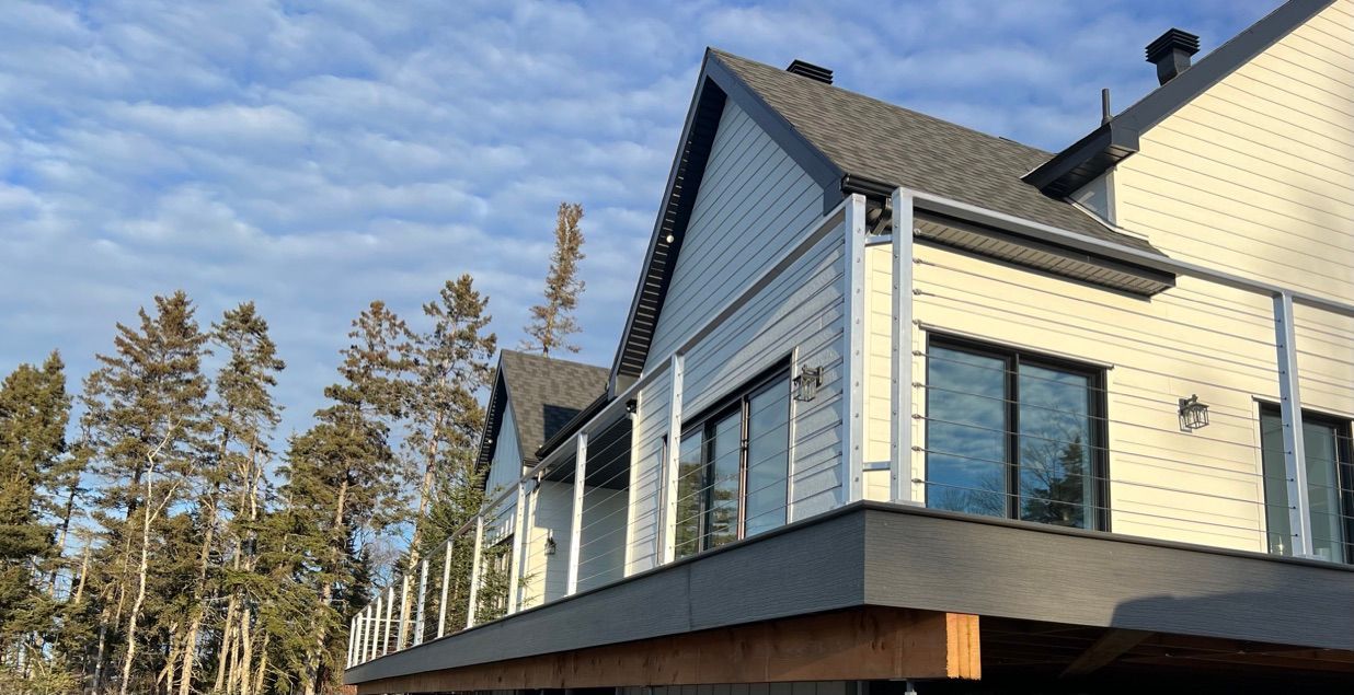 Une maison blanche avec un balcon et des arbres en arrière-plan.