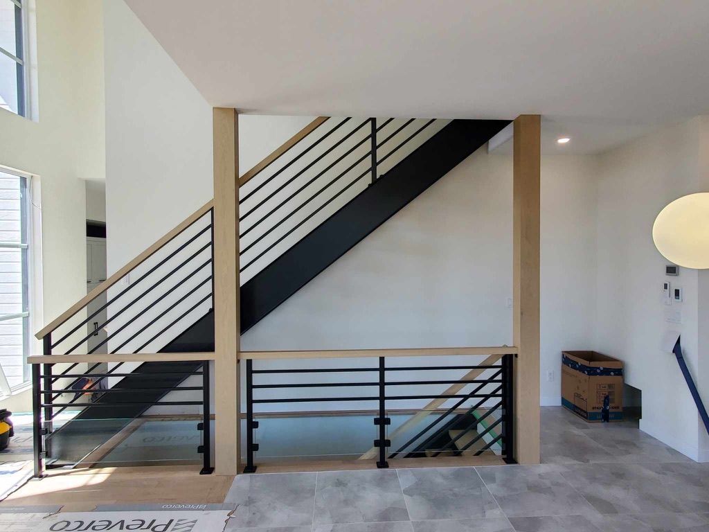 Un escalier avec une rampe noire et une main courante en bois