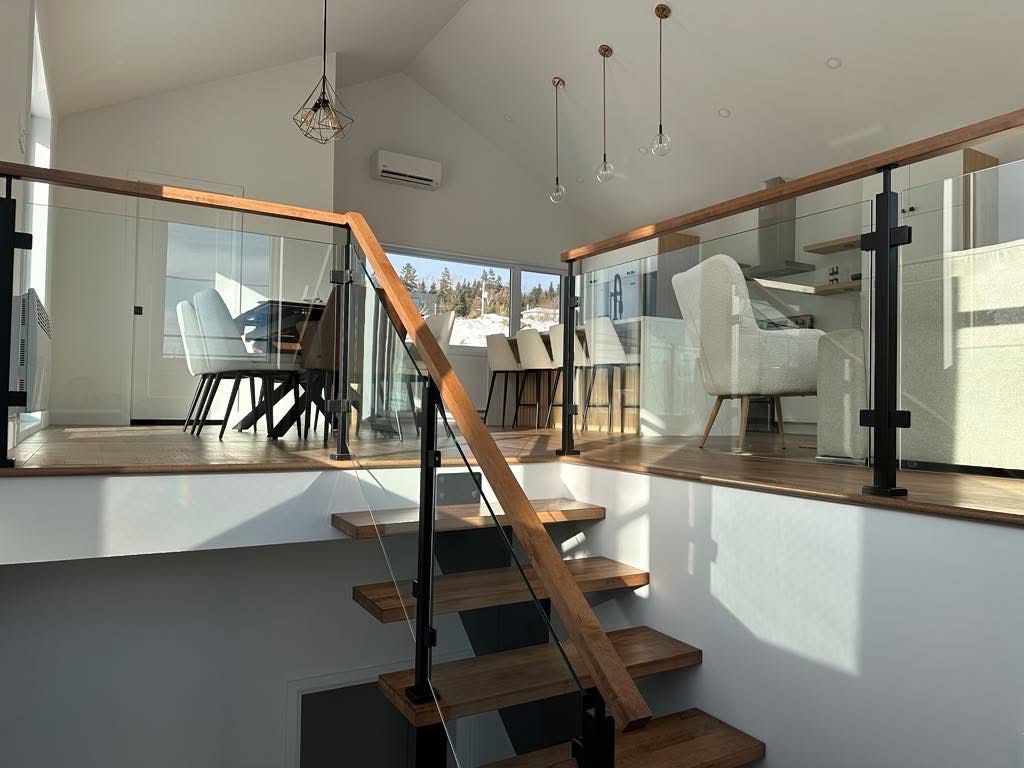 Un escalier menant au deuxième étage d'une maison avec une rampe en verre.