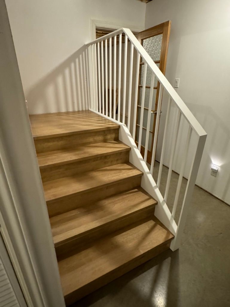 Un escalier en bois avec une rampe blanche dans un couloir.