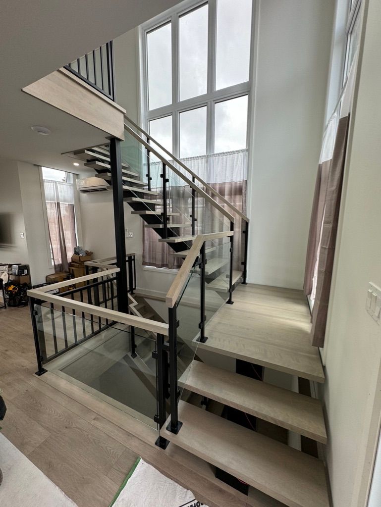 Un escalier en bois avec une rampe en verre dans une maison.
