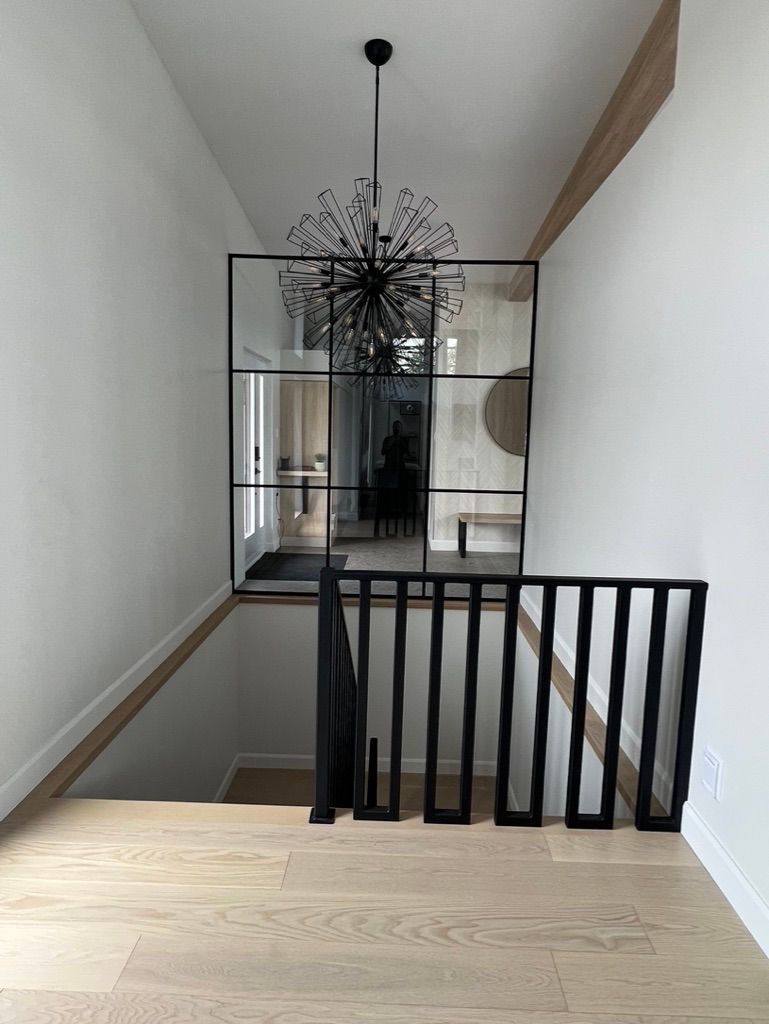 Un escalier avec une rampe noire et un lustre suspendu au plafond.