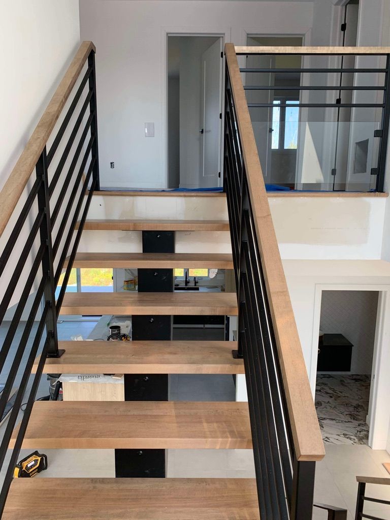 Un escalier avec des marches en bois et une rampe en métal dans une maison.