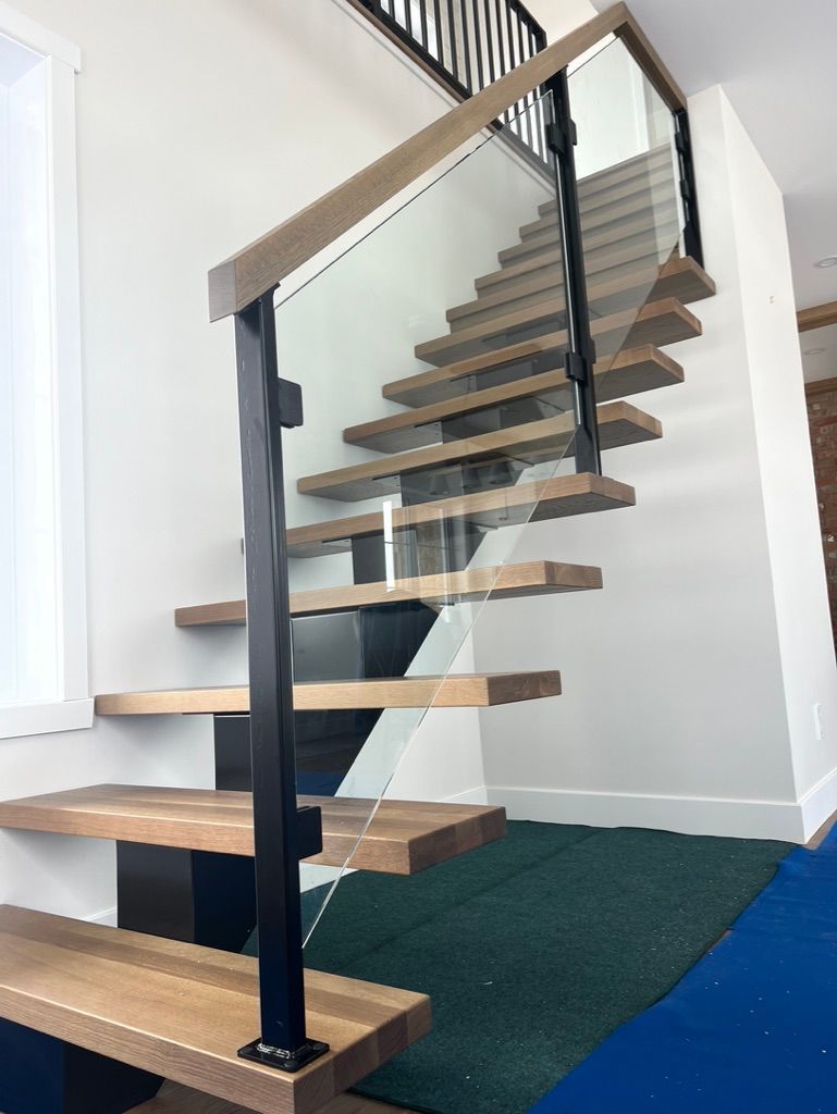 Un escalier en bois avec une rampe en verre dans une pièce.