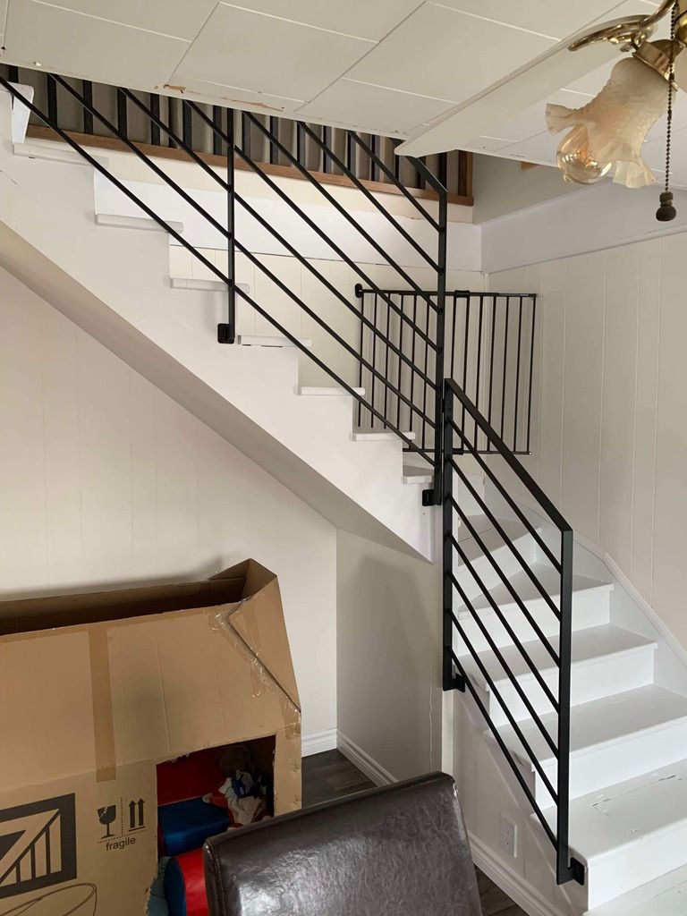 Un escalier blanc avec une rampe noire dans une pièce.