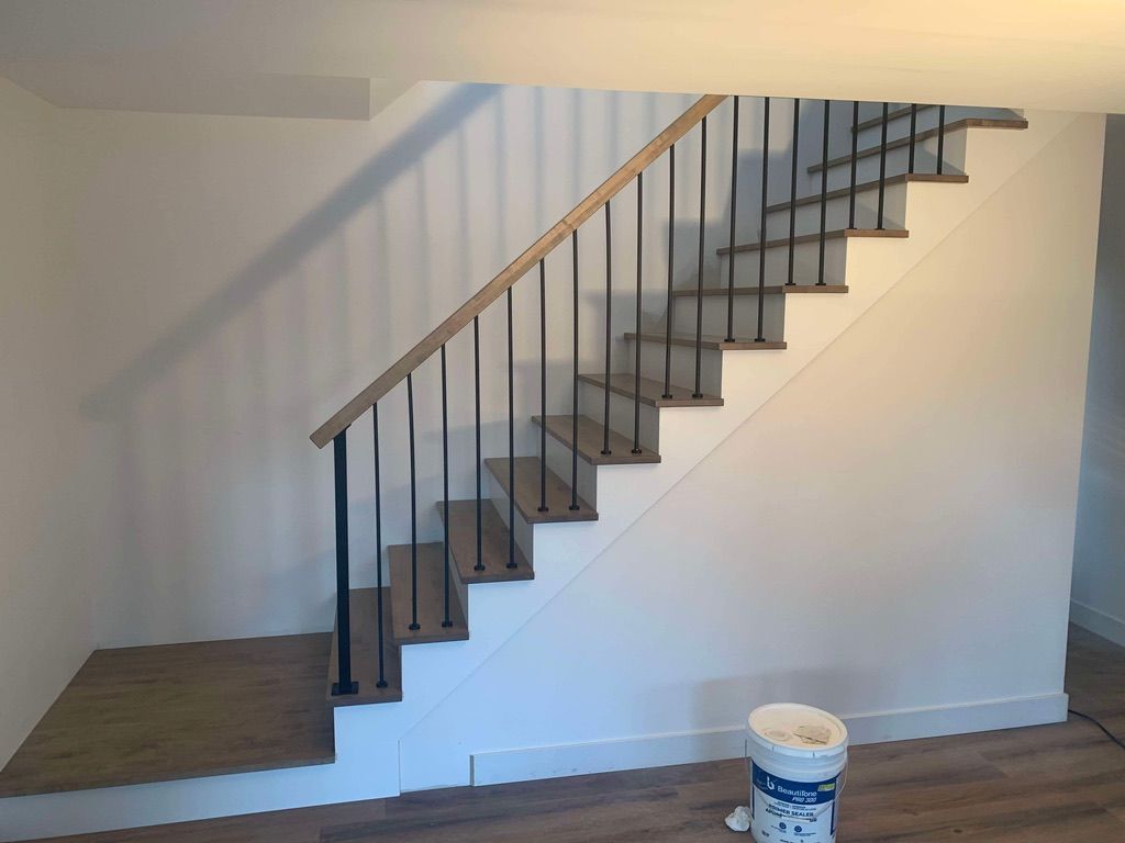 Un escalier en bois avec une rampe en métal dans une pièce.