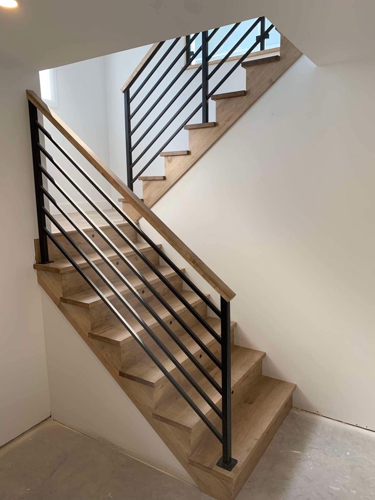 Un escalier en bois avec une rampe noire dans une pièce.