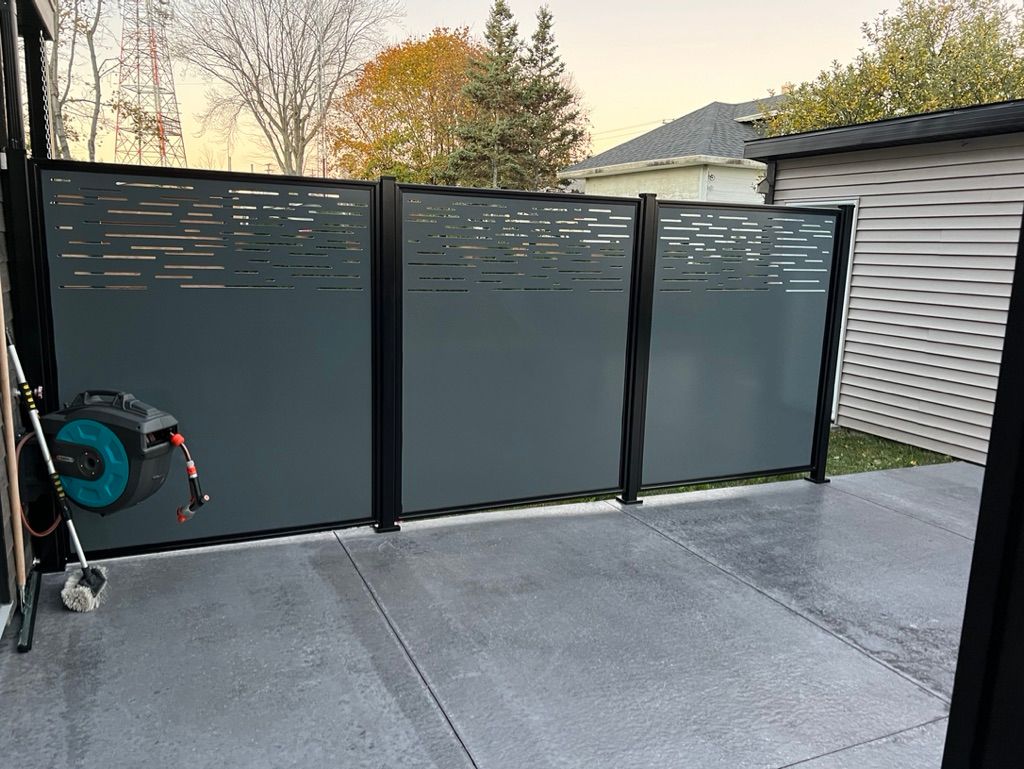 Un patio avec une clôture et un enrouleur de tuyau dessus.