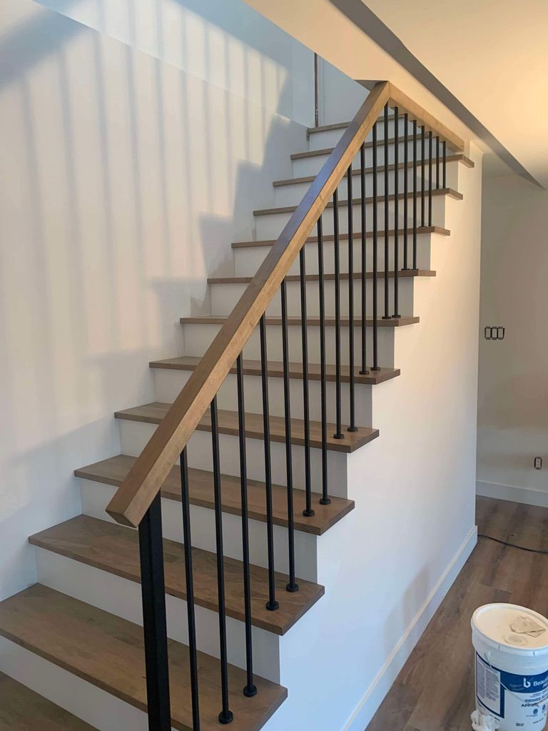 Un escalier en bois avec une rampe noire dans une maison.
