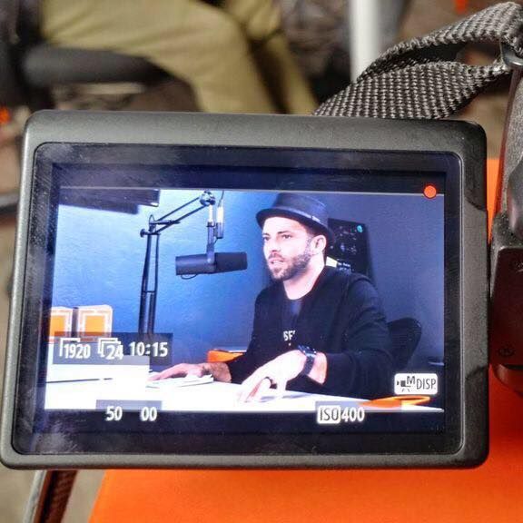 A man in a hat is sitting in front of a microphone