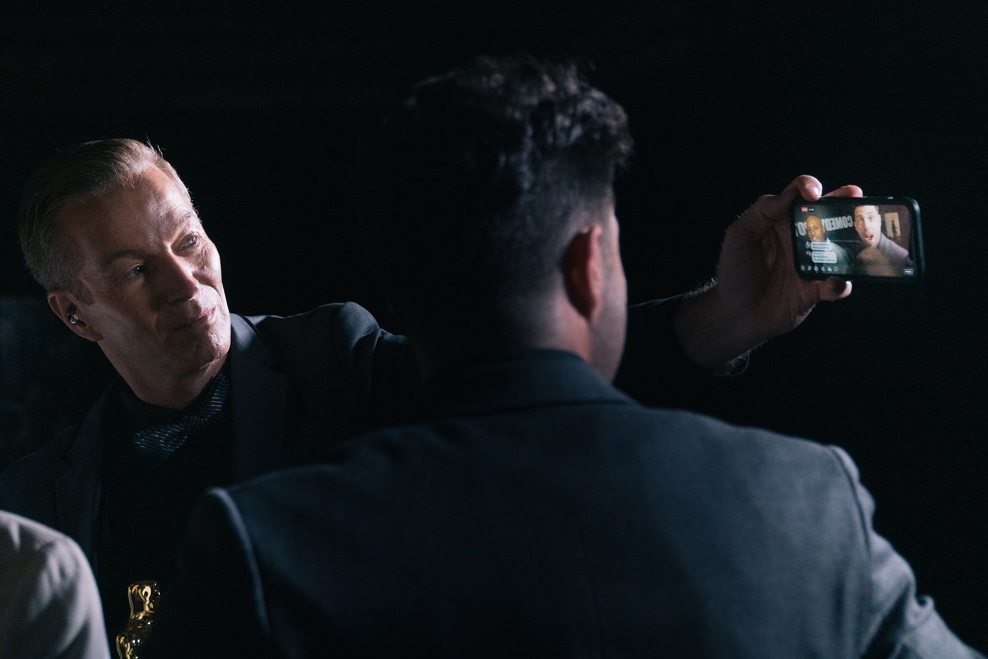 A man is taking a picture of another man with a cell phone.