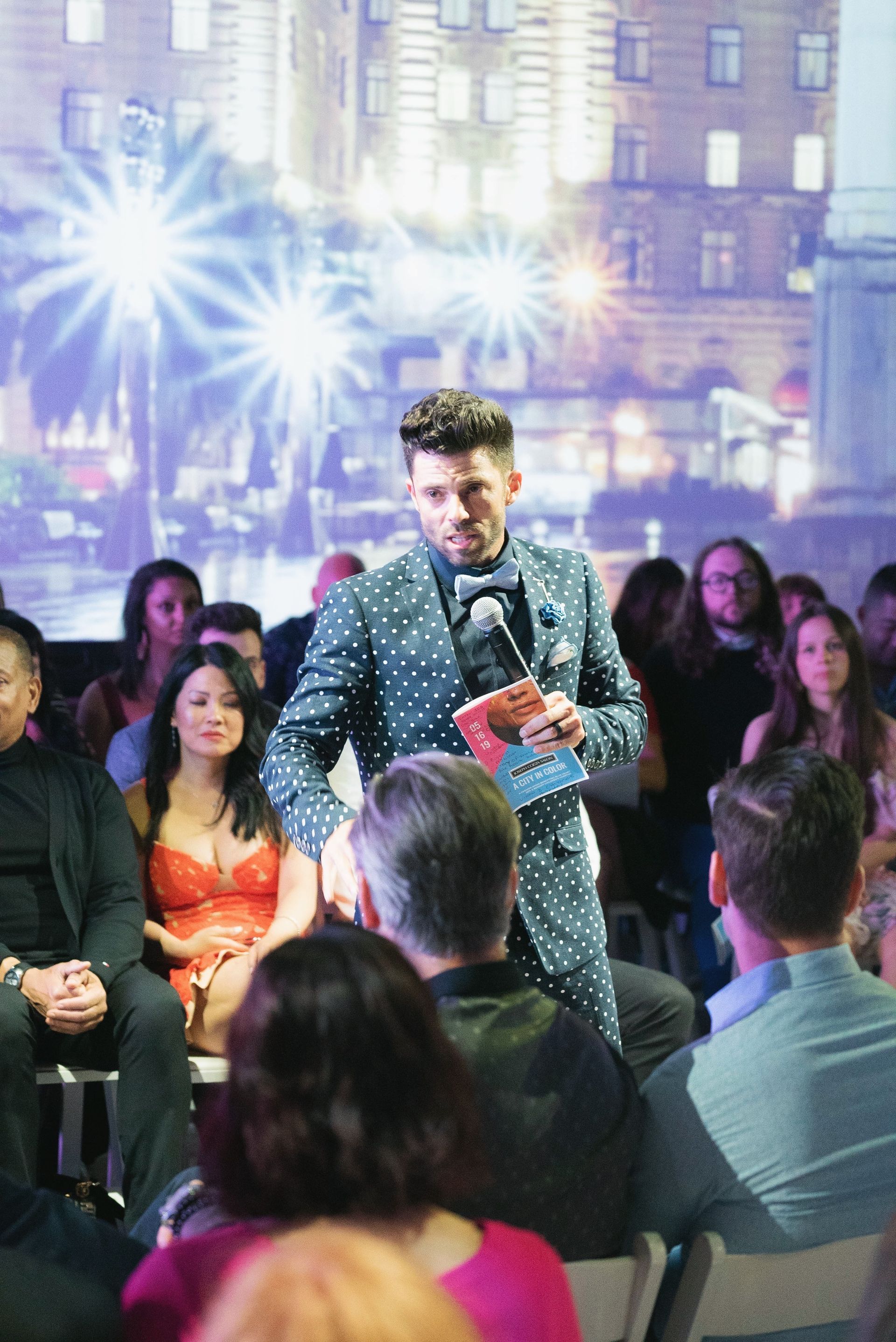 A man in a suit and bow tie is standing in front of a crowd of people.
